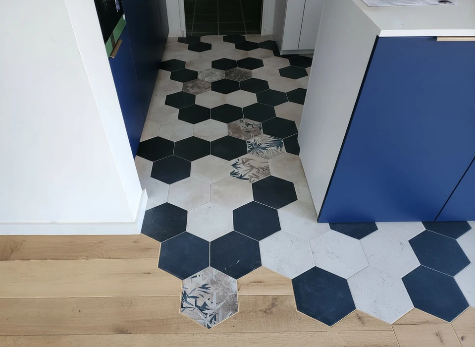 Salon moderne avec canapé blanc, coussins colorés, pouf jaune tricoté sur tapis géométrique noir et blanc