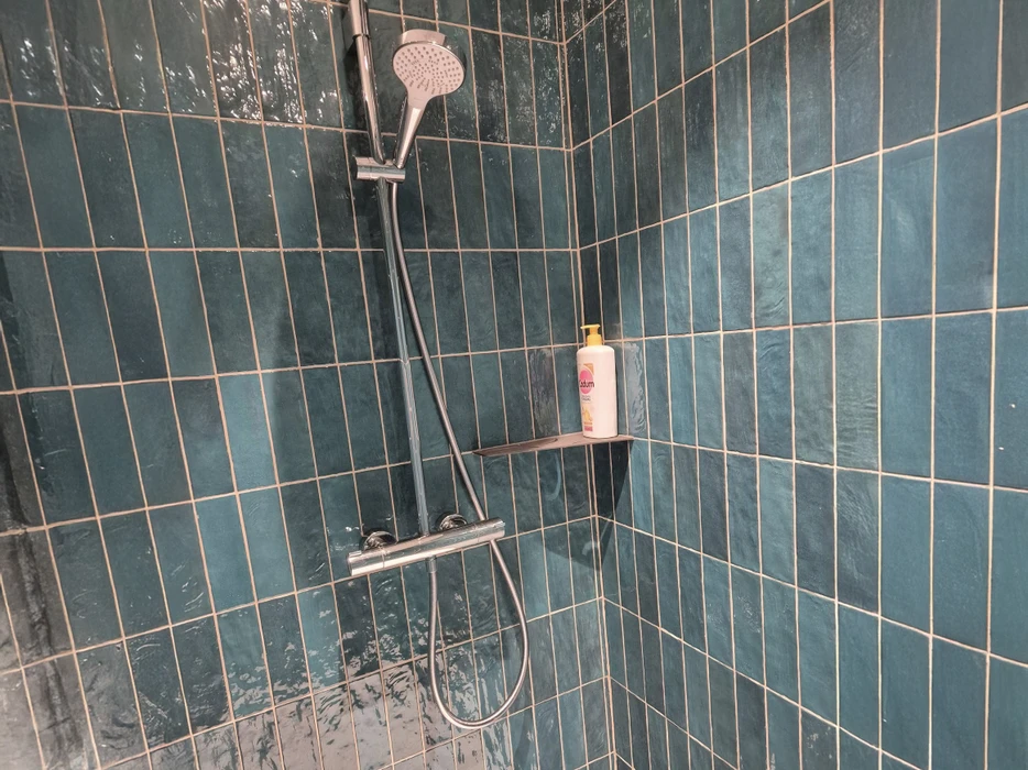 Salle de bain moderne avec baignoire encastrée, meuble vasque suspendu blanc, miroir rectangulaire et carrelage imitation bois au sol